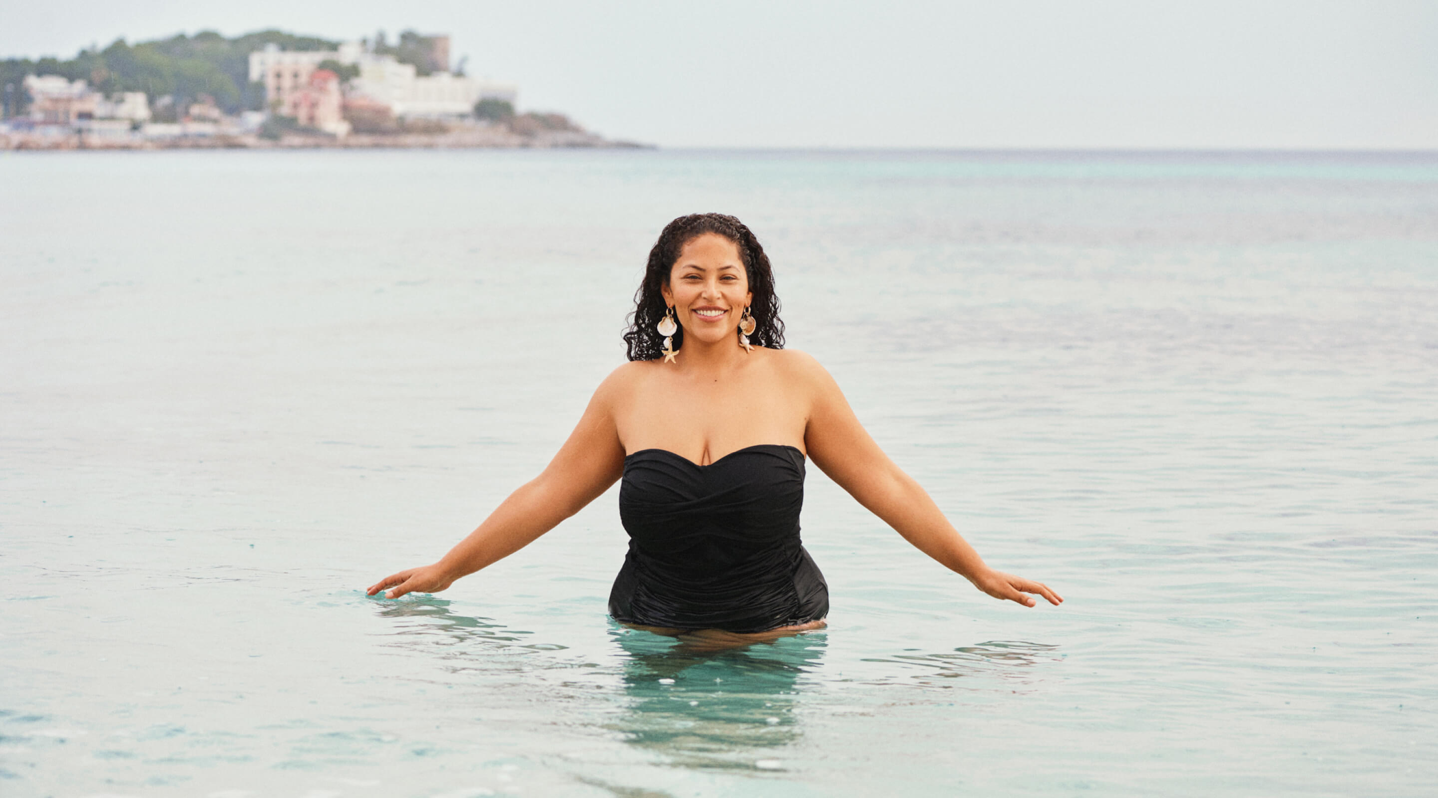 Modell i en vit bikinitopp vid hamnen med badare